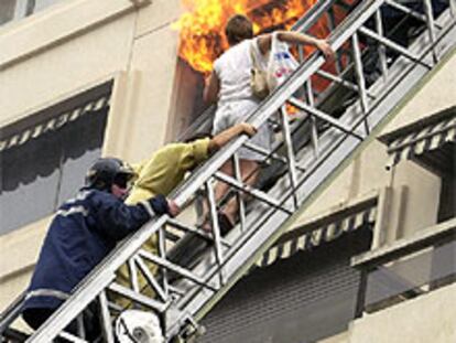 Los bomberos rescatan a una de las familias afectadas por un incendio en el número 24 de la calle Julio Palacios de Madrid.
