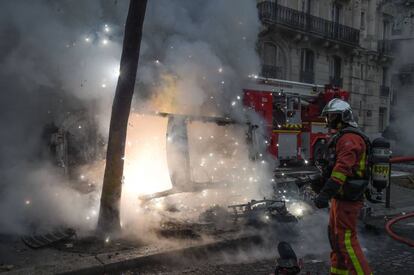 Un bombero junto a los restos de un coche calcinado este sábado durante la protesta de los 'chalecos amarillos' en la capital francesa.