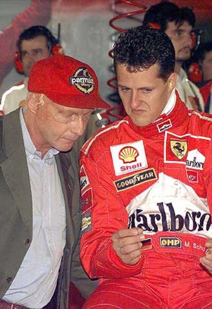 Niki Lauda escucha las explicaciones del piloto alemán Michael Schumacher en 1998 en el circuito de Monza (Italia).