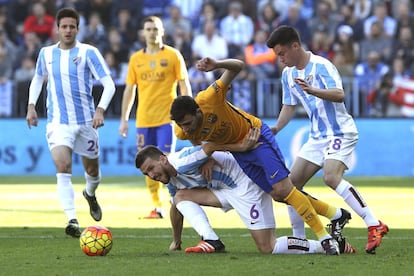 El delantero del FC Barceona Munir El Haddadi Mohamed (c) y los jugadores del Málaga, Ignacio Camacho (i) y Juan Pablo Añor "Juanpi" (d), durante el partido de la vigésima primera jornada de Liga de Primera División que se juega en el estadio de la Rosaleda en Málaga.