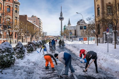 Vecinos de Madrid limpiando este domingo las calles de nieve.