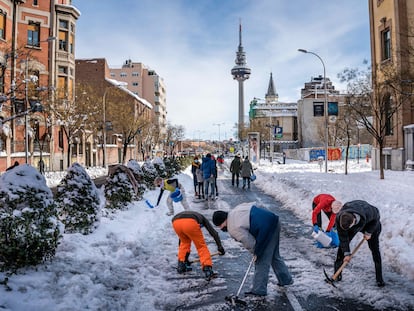 Vecinos de Madrid limpiando este domingo las calles de nieve.