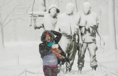 Una mujer posa para una fotografa debajo de una estatua cubierta de nieve, en el Monumento a los Veteranos de Vietnam, en Washington.