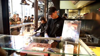 Dos camareros en un puesto del Mercado de San Miguel, en Madrid.