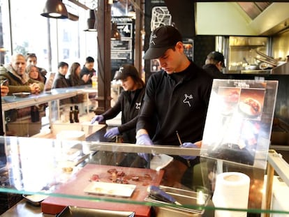 Dos camareros en un puesto del Mercado de San Miguel, en Madrid.