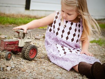 Una niña juega con un tractor viejo.