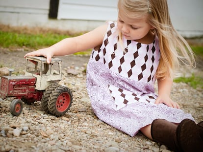 Una niña juega con un tractor viejo.