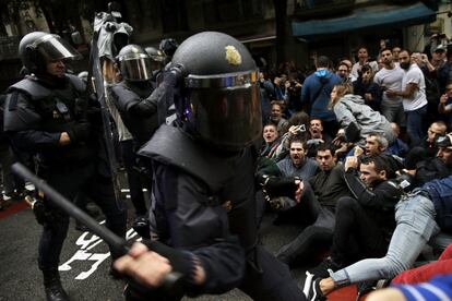 A Polícia Nacional tenta retirar os simpatizantes do referendo que se sentam em uma rua de Barcelona.