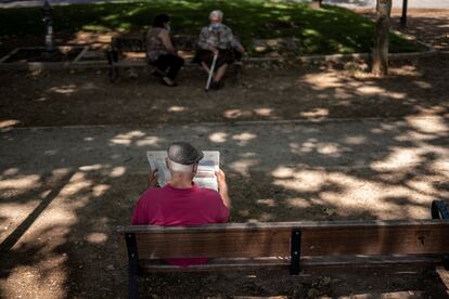 Un hombre lee EL PAÍS en un parque de Madrid.