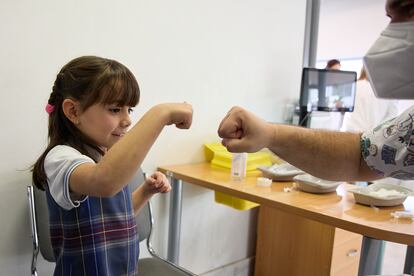 Una niña choca su puño con un sanitario tras recibir la primera dosis de la vacuna contra el covid-19, el miércoles en el hospital La Paz.