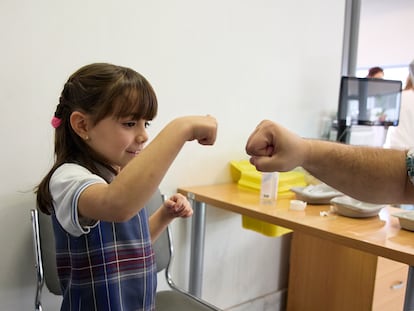 Una niña choca su puño con un sanitario tras recibir la primera dosis de la vacuna contra el covid-19, el miércoles en el hospital La Paz.