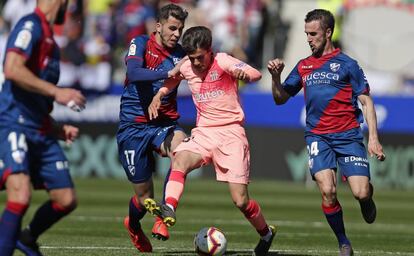 Riqui Puig controla el balón ante tres jugadores del Huesca en El Alcoraz.