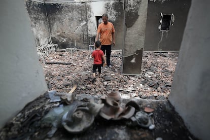 Un hombre argelino con su hijo inspecciona su casa quemada en el pueblo de Oeud Das, en Bejaia, Argelia, este martes.