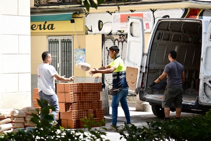 Trabajadores autónomos descargan sacos de arena en la madrileña calle del Limón, el 19 de julio, a una temperatura que ronda los 40 grados bajo el sol.