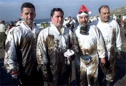 Cuatro de los voluntarios que ayer participaron en las tareas de recogida de chapapote en la playa de Pedriña (Muxía).