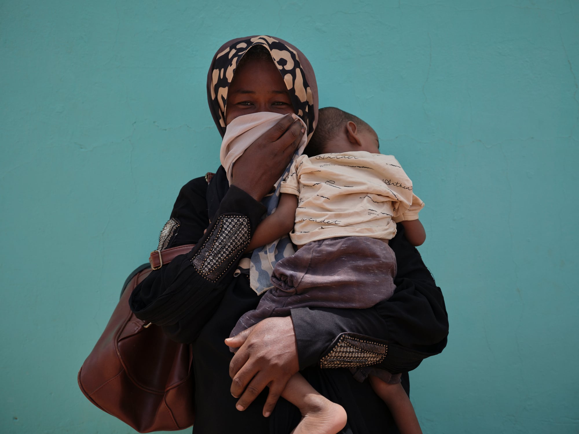 Marwa Alswar, de 35 años, sostiene en brazos a su hijo Khalid Yasser, de dos años, mientras posa para un retrato en el patio de un centro de salud de Jebel Awlia, a 40 kilómetros al sur de Jartum.