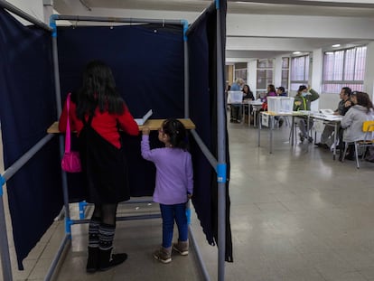 Una mujer junto a su hija dentro de una urna electoral en el Colegio Víctor Jara, La Pintana (Santiago).