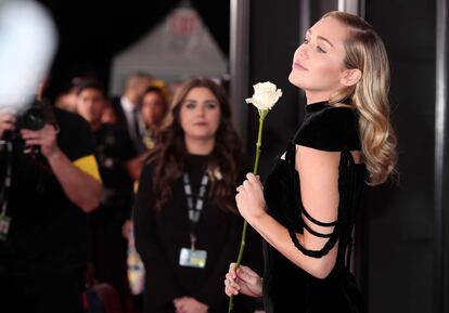 Miley Cyrus con melena ondulada y maquillaje natural posando con la rosa, símbolo contra el acoso sexual y apoyo al movimiento #MeToo.