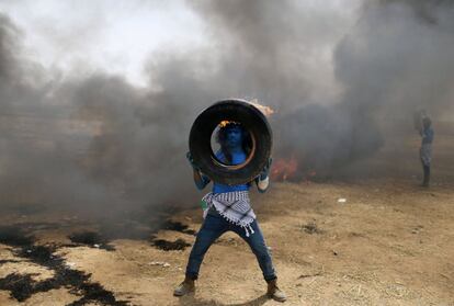 Un manifestante con la cara pintada como la película 'Avatar' sujeta un neumático en llamas durante una protesta entre la frontera de Israel con Gaza, al sur de la Franja de Gaza.