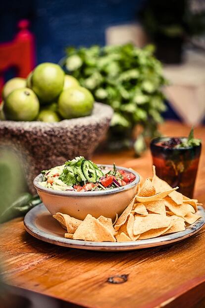 <p><i>Ingredientes</i></p><p> Para 4 personas: 4 aguacates maduros, 1 cebolla, 2 tomates, 4 ramas de cilantro, 1 chile jalapeño, zumo de limón, sal. Para acompañar: totopos de maíz crujientes.</p><p><i> Preparación</i></p><p> 1. Cortar el tomate, la cebolla y el chile en daditos. 2. Picar el cilantro. 3. Machacar los aguacates con un tenedor, desmontándolo un poco, pero dejando pedazos enteros para darle textura. 4. Mezclarlo todo y añadir zumo de limón y sal al gusto. 5. Dejar un par de huesos del aguacate dentro del guacamole para evitar que se oxide y servir acompañado de totopos de maíz.</p>