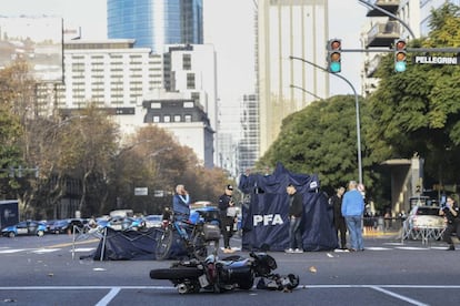 La moto de los ladrones, destrozada sobre el asfalto. Detr&aacute;s, la polic&iacute;a protege de la vista los cad&aacute;veres de los dos ladrones.