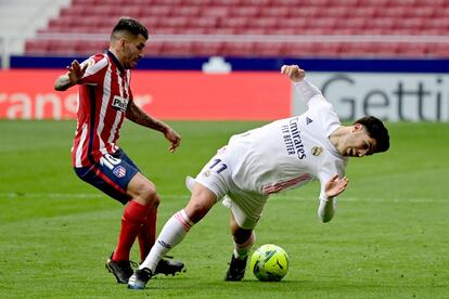 El delantero del Real Madrid Marco Asensio cae ante el centrocampista argentino del Atlético de Madrid Ángel Correa.