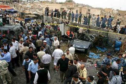 Policías y civiles rodean los restos del coche bomba que explotó en Nayaf.