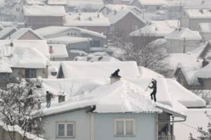 Hombres quitan la nieve acumulada en los tejados tras las intensas nevadas de los últimos días, en la localidad de Zhur, al sur de Kosovo. EFE/Archivo