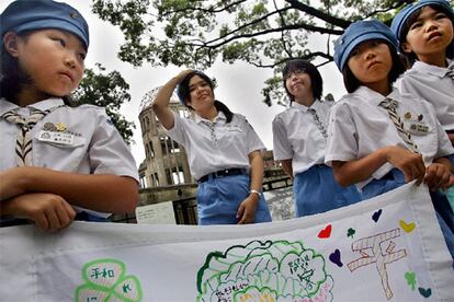 Varias colegialas llevan, como ya es habitual en la ciudad, una pancarta con mensajes de paz en el Parque Memorial de la Paz de Hiroshima. Detrás de ellas se levantan las ruinas del antiguo Salón Provincial de Exposiciones, milagroso superviviente de la bomba.