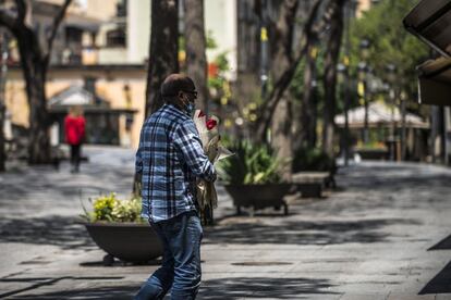 Un home passeja per una Girona mig buida amb una rosa.