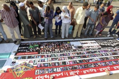 Un grupo de personas observa una pancarta con fotos de los maniefstantes muertos en las protestas de la Plaza Tahrir en enero y febrero.