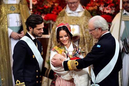 Carlos Felipe y Sof&iacute;a de Suecia, con el pr&iacute;ncipe Gabriel en brazos, y el rey Carlos Gustavo en la capilla del palacio de Drottningholm en Estocolmo.