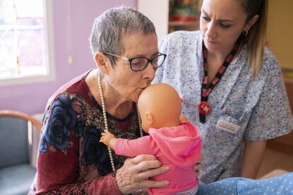 Mari Fe Lorente da un beso a uno de los muñecos. A su lado, la terapeuta ocupacional, Ana Sanz. Todo el personal del centro está formado, desde las auxiliares hasta el personal de cocina. Deben tratar a los muñecos como a bebés porque quienes participan en la terapia creen que lo son.