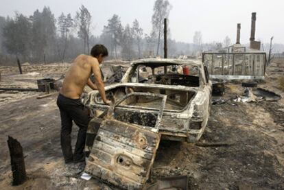 Un hombre observa un coche calcinado por un incendio en Peredeltsy, al sureste de Moscú.