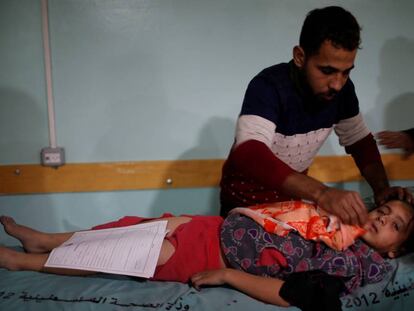 Un hombre atiende en un hospital a una ni&ntilde;a herida el s&aacute;bado en el bombardeo israel&iacute; sobre Gaza.