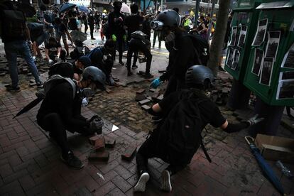 Los manifestantes levantan el pavimento para recoger ladrillos, durante las manifestaciones en el distrito de Wanchai, en Hong Kong.