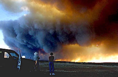Dos vecinos de Show Low (Arizona) observan el impacto de las llamas en las inmediaciones de su ciudad.