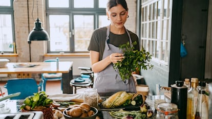 Mujer cocinando con hierbas aromáticas.