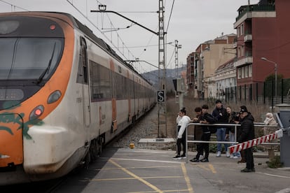 Varios peatones esperan a que pase el tren.
