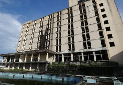 Vista de la fachada del antiguo Hotel Ducor en Monrovia, Liberia, el 1 de octubre de 2017. El hotel Ducor fue en su día el más prominente de África. Construido en el punto más elevado de Monrovia por el israelí Moshe Mayer en 1960, cerró sus puertas 29 años después tras haber sido el primer establecimiento hotelero de 5 estrellas en el continente. Frecuentado por políticos, diplomáticos y empresarios de toda África y extranjero, fue un ejemplo de los años prósperos que vivió en aquella época la África occidental. Sus instalaciones acogieron numerosas reuniones entre líderes africanos y numerosas anécdotas envuelven su historia, como una del dictador ugandés Idi Amin, de quien se dice que se zambulló en su piscina con pistola incluida. El Ducor fue usado tamibén como posicionamiento de tiro por los compatientes del ex presidente liberiano Charles Taylor durante el sitio de Monrovia por las fuerzas rebeldes en 2003. Desde entonces, una espesa vegetación rodea cada uno de los rincones de este edificio desértico de estilo art déco.