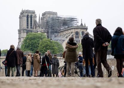 Los parisinos observan la catedral de Notre Dame al día siguiente del fuego que casi la destruye.