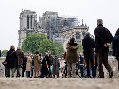 Los parisinos observan la catedral de Notre Dame al día siguiente del fuego que casi la destruye.