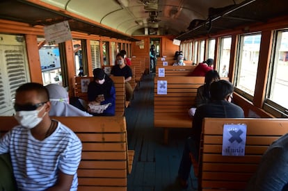 Los pasajeros se sientan respetando las indicaciones de distanciamiento social, tras el levantamiento de las restricciones de viaje para detener la propagación del coronavirus, en la estación de ferrocarril de Tanyong Mat, en la provincia meridional tailandesa de Narathiwat.