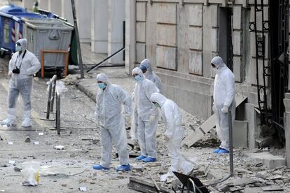 Expertos forenses buscan pruebas en una calle donde una bomba estalló frente a unas oficinas de una federación empresarial griega, en el centro de Atenas (Grecia).