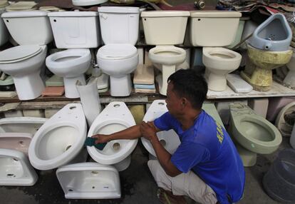 Un hombre limpia los sanitarios que vende por 27 euros cada uno en una tienda del centro de Manila, Filipinas.