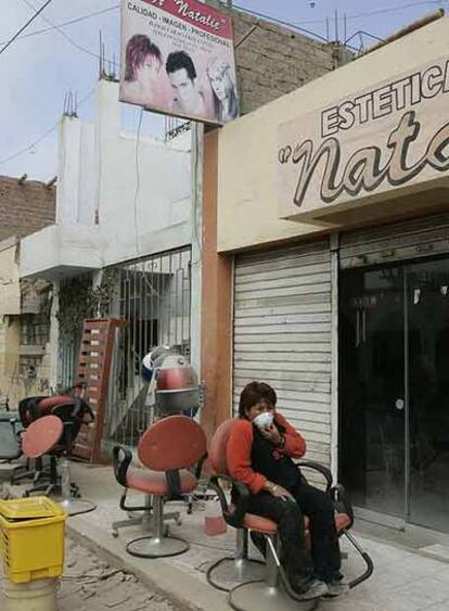 Una mujer se protege con una mascarilla a las puertas de una peluquería.