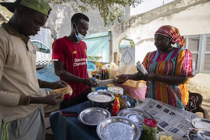 El puesto de Bintou Sane está en el barrio de Ouakam. Por allí pasan cientos de personas cada día para tomar su desayuno. “Estudié contabilidad, pero es muy difícil encontrar trabajo, y como no puedo estar parada, monté este puesto delante de mi casa para ganarme la vida. Con lo que gano estoy ahorrando para poder construir un espacio donde no me molesten el polvo y la arena, o el humo de los coches, quiero ofrecer un mejor servicio a mis clientes. A veces las condiciones de trabajo son duras”, explica.