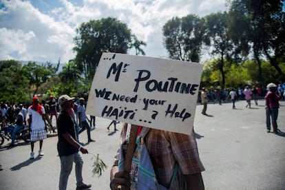 Um homem segura um cartaz que diz "Sr. Putin, precisamos da sua ajuda, Haiti", durante um protesto na quarta-feira, 13 de fevereiro, em Porto Príncipe.