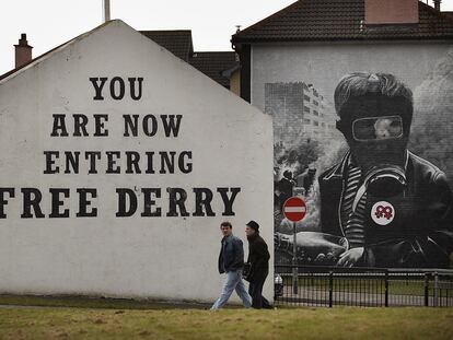 Dos personas caminan frente a un cartel en una fachada donde se puede leer "Estás entrando en la Derry libre" en el año 2010.