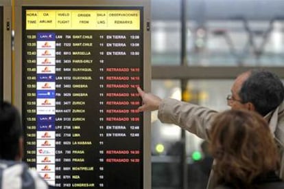 Unos pasajeros consultan ayer un panel de información en la T-4 del aeropuerto de Barajas (Madrid).